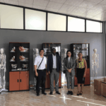MeCan Medical team posing with Zambian university procurement officers in an anatomy lab equipped with skeleton models.