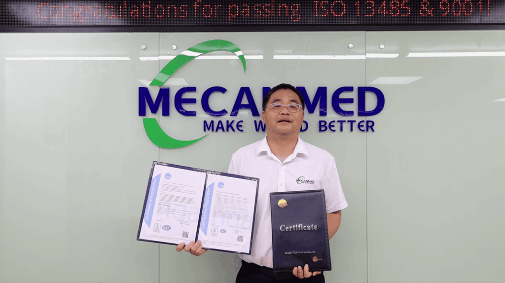 MeCanMed founder Andy holding the official ISO 13485 and ISO 9001 quality certificates in front of company logo.